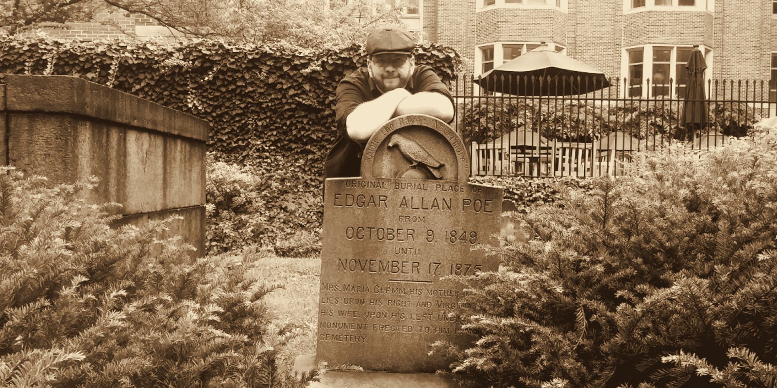 Vince Wilson leaning on the raven headstone at Poe's original burial place